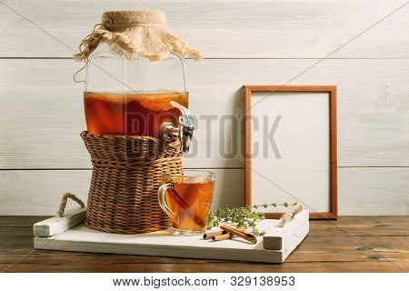 Fresh Homemade Kombucha Fermented Tea Drink In A Jar With Faucet And In A Cup On A White Tray, Frame