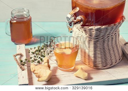 Fresh Homemade Kombucha Fermented Tea Drink In A Jar With Faucet And In A Cup And In Mug On A White 