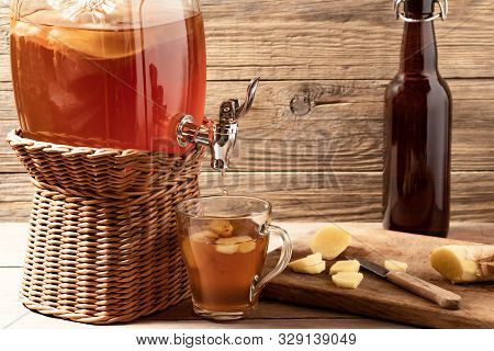 Fresh Homemade Kombucha Fermented Tea Drink In Jar With Faucet And In Cup And Bottle On Wooden Backg