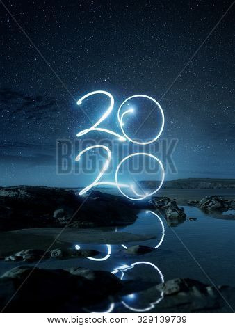 Happy New Year2020 Light Effect Writing Reflecting In Water On A Beach At Night. Long Exposure Lands