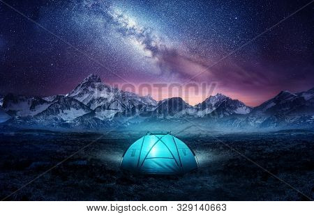 Camping In The Mountains Under The Stars. A Tent Pitched Up And Glowing Under The Milky Way. Photo C