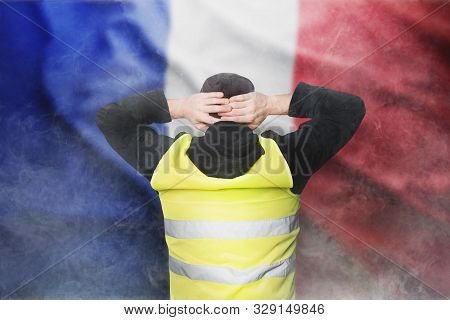 Yellow Vests Protests. A Young Man Stands With His Back And Holds His Hands On His Head As A Sign Of