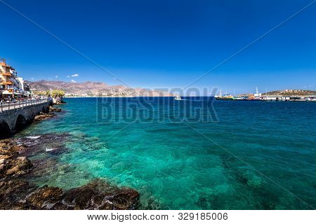 Agios Nikolaos Coastline On A Sunny Day With Clear Sea And Cliffs.