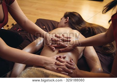 Two Massage Therapist Doing Healing Massage, Massage In Four Hands. Woman Enjoying In Relaxing Massa