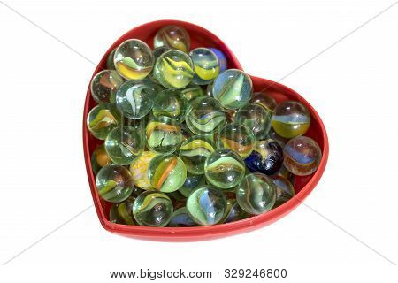Brightly Colored Marbles In A Heart Shaped Box With A White Background