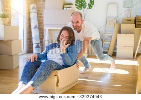 Funny and crazy couple having fun riding a cardboad box as a car, smiling happy and lauging at new home