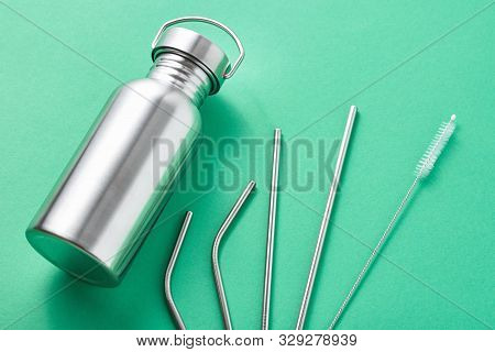 Reusable Plastic Free Items On Green Background. Top View Of Aluminun Bottle And Metal Tubes. Zero W