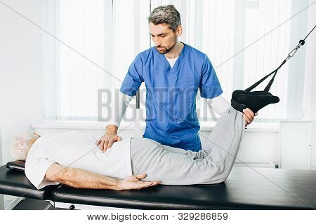 Kinesiologist Doing Therapeutic Exercises For An Elderly Patient. Kinesitherapy At The Medical Cente
