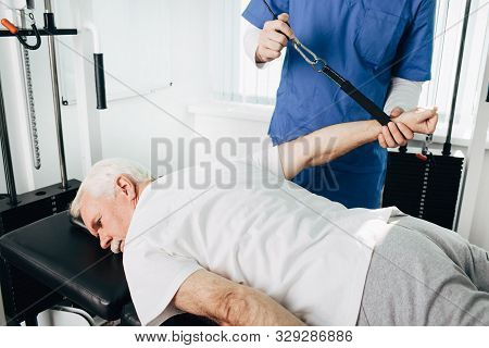Kinesiologist Doing Therapeutic Exercises For An Elderly Patient. Kinesitherapy At The Medical Cente
