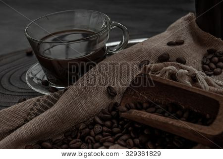 Coffee Style, Cup Of Coffee And Coffee Beans Roating With Old Wooden Scoop And Coffee Beans Around O