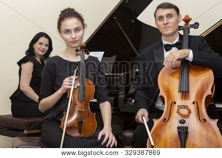 Family Music Trio. A Young Violinist And Cellist Play, The Pianist Accompanies Them.