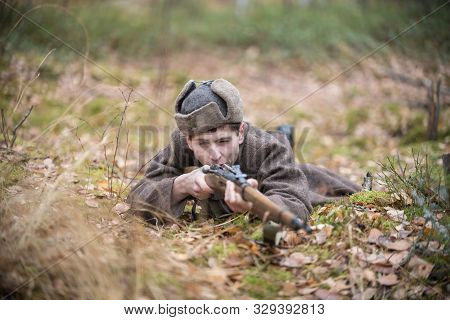 A Soldier Of World War Ii Is Lying In The Forest And Aiming