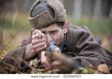 A Soldier Of World War Ii Is Reloading The Rifle While Lying On The Battlefield