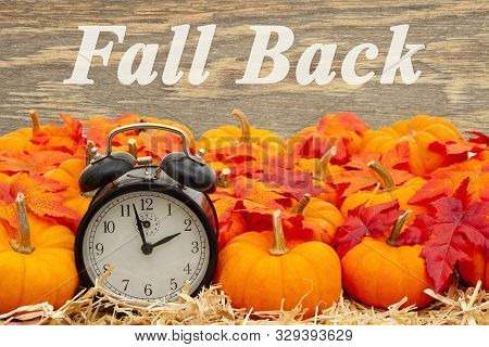 Fall Back Time Change Message With A Retro Alarm Clock With Orange Pumpkins With Fall Leaves On Stra