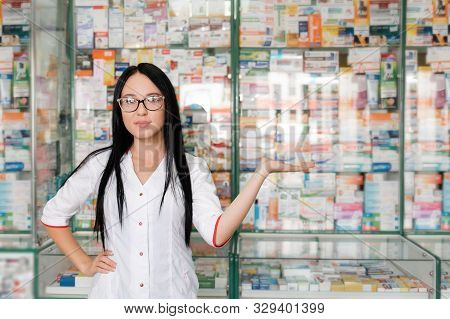 Pharmacy And Pharmacist-seller. Female Pharmacist With Glasses Posing On The Background Of Shop Wind