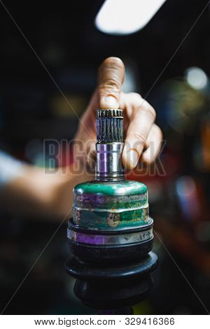 hand holding ATV constant-velocity CV joint, repair in old garage