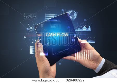 Businessman holding a foldable smartphone with CASH FLOW inscription, successful business concept