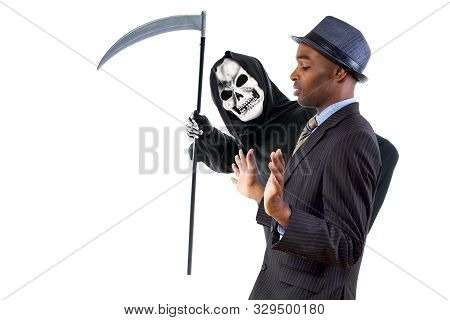 Man In A Grim Reaper Halloween Ghost Costume Having Fun And Scaring A Grown Businessman In A Suit.  