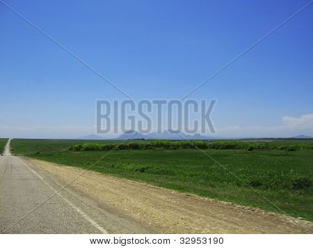 Wide Highway And Mountain. Clouds Over And Blue Sky