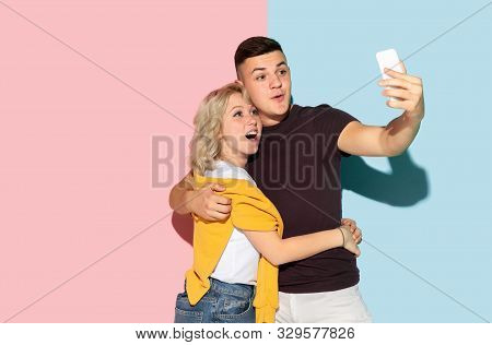 Young Emotional Man And Woman In Bright Casual Clothes Posing On Pink And Blue Background. Concept O