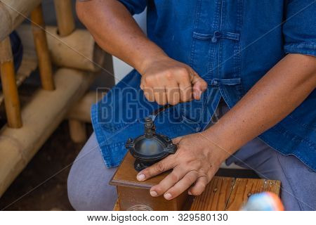 Man Grinds With An Old Coffee Mill With Crank Fresh Coffee Powder For Coffee.