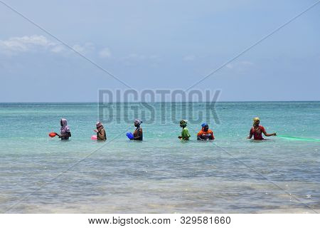Kendwa, Zanzibar - October 3, 2019: Local Women In Traditional Dress Fishing In The Ocean During Low
