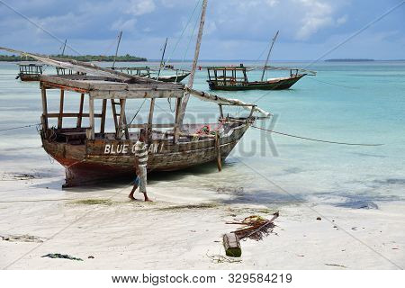 Kendwa, Zanzibar - October 4, 2019:  Local Man And Fishing Boats On The Kendwa Beach Shown During Lo