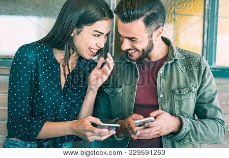 Happy Young Couple Having Fun With Mobile Smart Phone At Urban Place - Friendship Concept With Best 