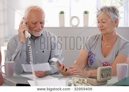 Ældre par kontrol regninger i hjemmet, diskuterer finanser.