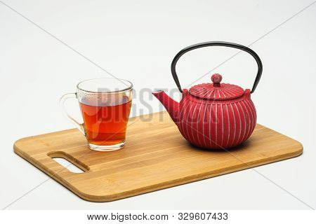 Cast-iron Teapot On A Wooden Board And A Glass Cup With Hot Tea On A White Background.