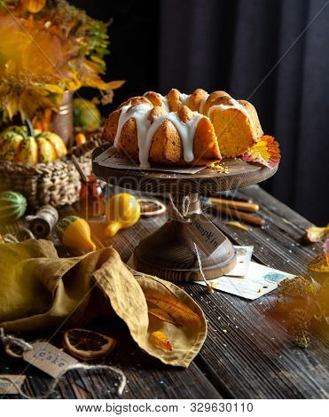 Homemade Tasty Baked Bundt Pumpkin Cake On Wooden Cake Stand On Rustic Table With Assorted Small Pum