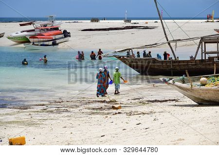 Kendwa, Zanzibar - October 4, 2019: Local Women In Traditional Dress Fishing In The Ocean During Low