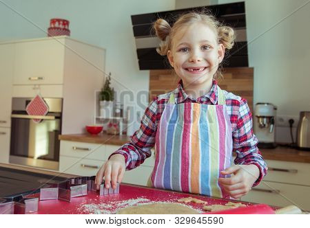Portrait Of Pretty Little Girl With  Funny Pigtails Decoraiting Christmas Cookies