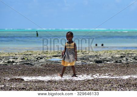 Pingwe, Zanzibar - October 6, 2019: Smiling Happy Baby Girl On The Indian Ocean Coast During Low Tid