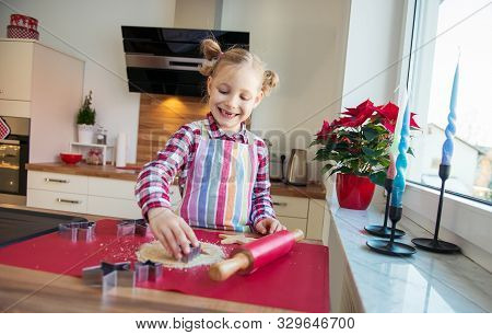 Pretty Little Girl With Funny Pigtails Decoraiting Christmas Cookies Of Different Forms In Kitchen