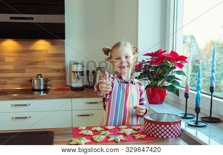 Portrait Of Pretty Little Girl With  Funny Pigtails Decoraiting Christmas Cookies