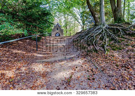 Dirt Path With A Metal Railing And A Tree With Bare Roots That Leads To The Chapel Of Mary Or Chapel