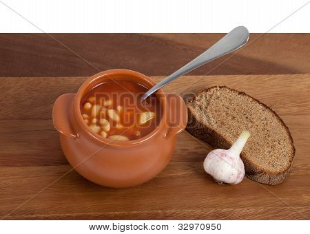 Soep In keramische Pot met brood en knoflook op houten tafel