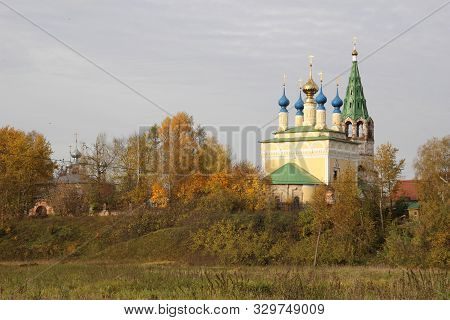 Landscape With Goritsy Village Church Among Autumn Colorful Trees With Blue Cloudy Sky
