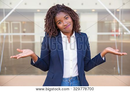 Positive Confused Female Agent Posing Outside. Young Black Business Woman Standing Near Outdoor Glas
