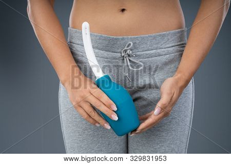 Woman Holding Vaginal Wash Against Gray Background