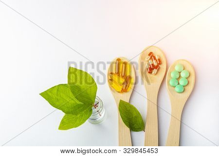 Herbal Capsule, Natural Vitamins, Mineral Supplement At Wooden Spoon On A White Background. Concept 