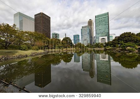 Tokyo, Japan, Buildings Reflected In A Pond In Kyu Shiba Rikyu Garden, On A Cloudy Day