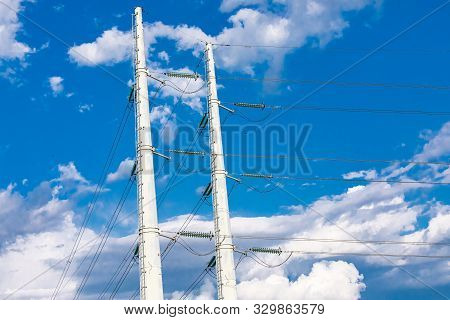 A Low Angle View Of Twin Electric Poles Supporting Medium Voltage Wires With Insulators And Access L