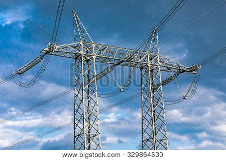 A Low Angle View Of A Double Lattice Pylon With High Volt Overhead Power Lines. Electric Transmissio