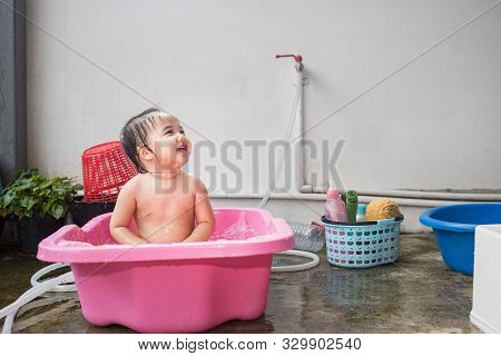 Asian Woman Washing Her Daughter In Bathtub, Baby Girl Taking A Bath In Pink Tub