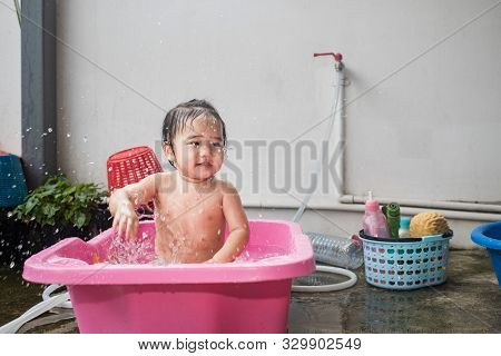 Asian Woman Washing Her Daughter In Bathtub, Baby Girl Taking A Bath In Pink Tub