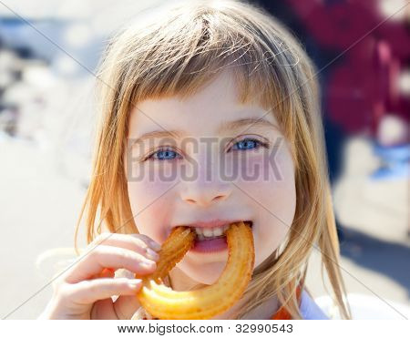 Occhi blu bambina mangiare krapfen fritti churros sorridente