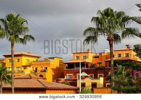 View On Playa De Las Americas On Canary Island Tenerife With Plam Trees, Orange Colored  Houses And 