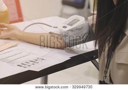 Women Are Using Blood Pressure Monitors For Annual Health Checks. Heart Rate Monitor On Wooden Table